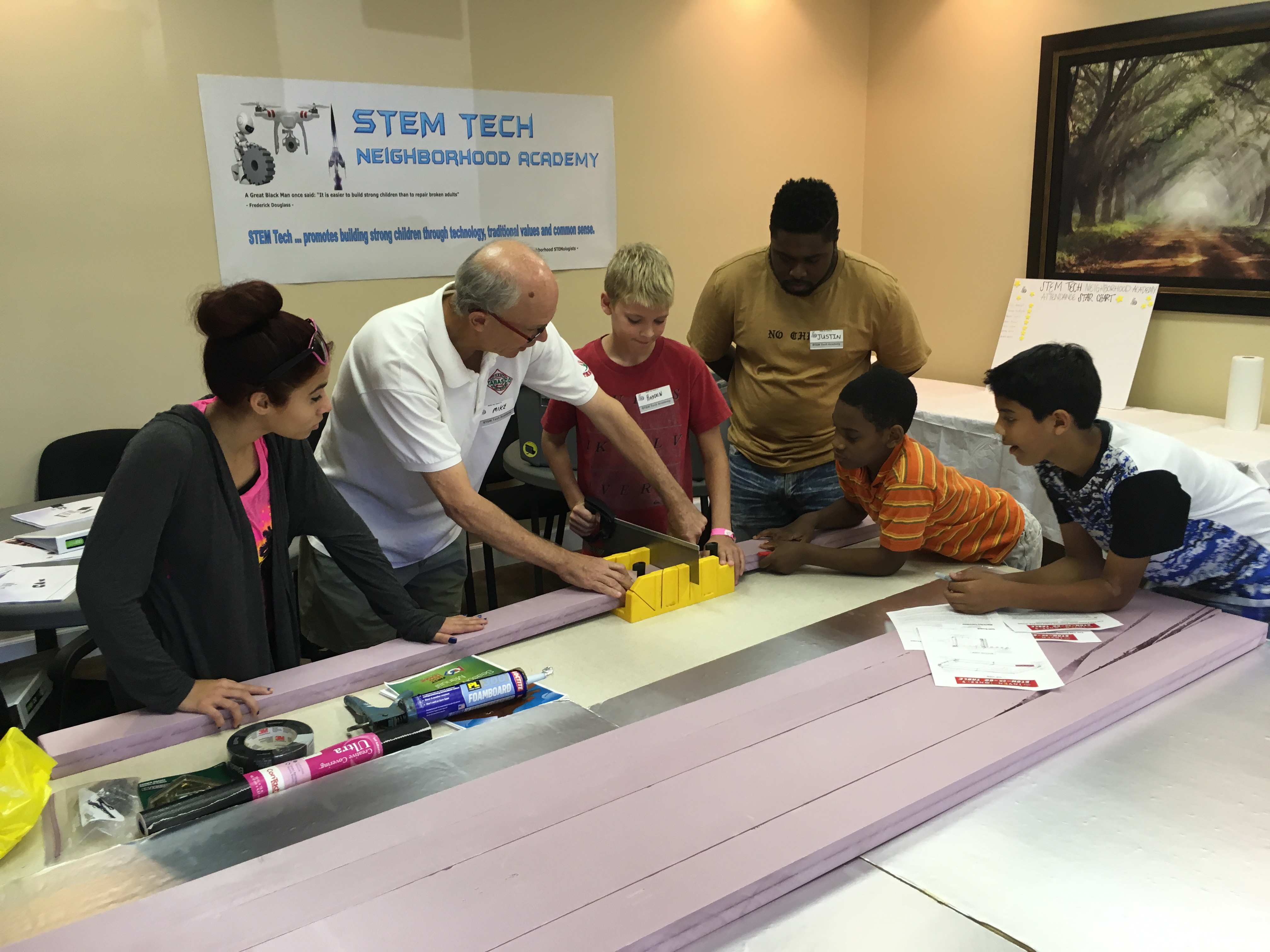 Instructor working with students on a project involving paper and scissors