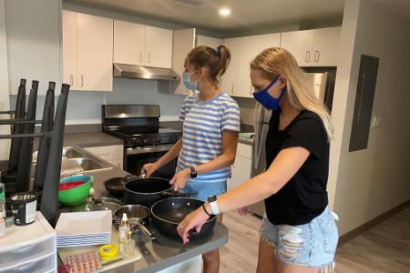 Students moving into their dorm, unpacking in the kitchen