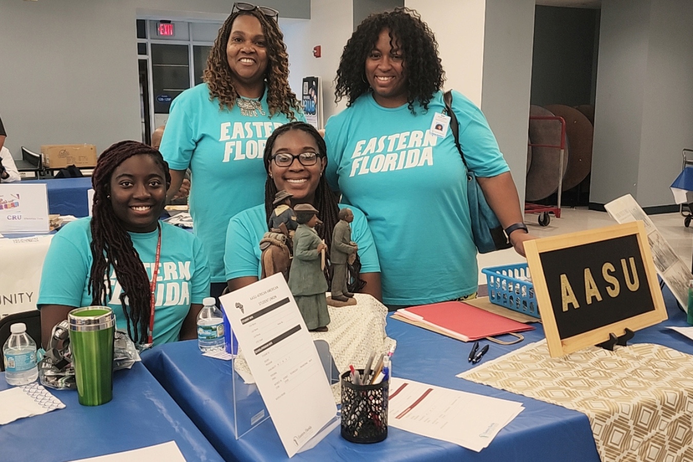 Students wearing Eastern Florida shirts at a booth during a Welcome Back event to promote their student club, the African American Student Union.