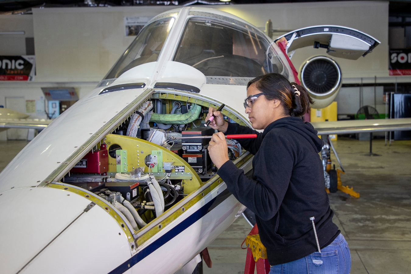 Female student gaining practical experience in aviation maintenance by working on an airplane at EFSC