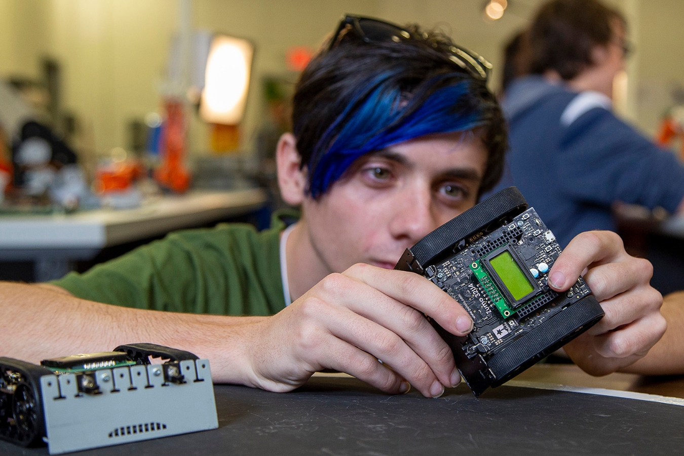 Close-up of a determined male student working on a robotics project in the engineering-tech program.