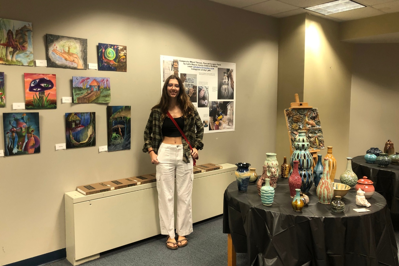 Student posed with artwork at a community gallery on campus
