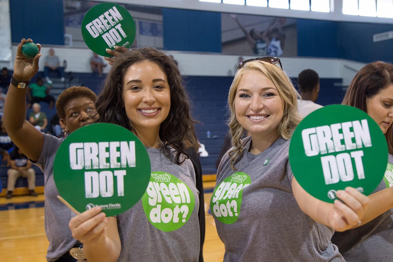 Two people holding up Green Dot signs