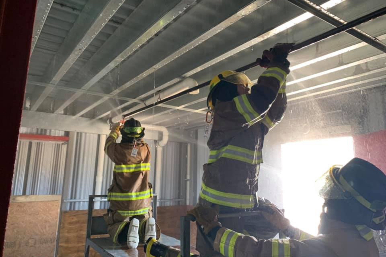 firefighter students participating in a training activity at the fire academy building working with a sprinkler system