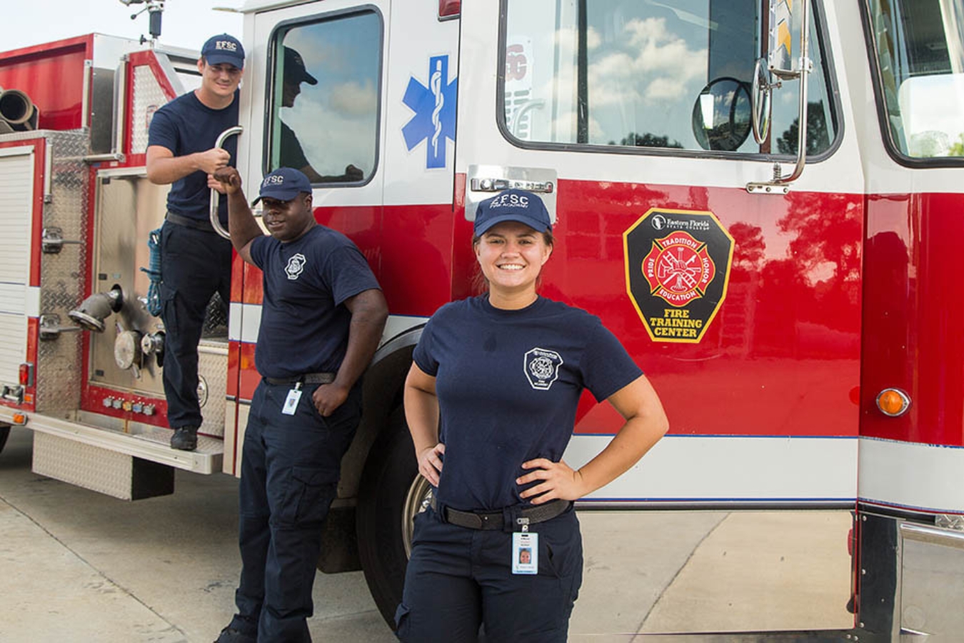 Group photo of fire science/firefighter students standing beside a fire truck