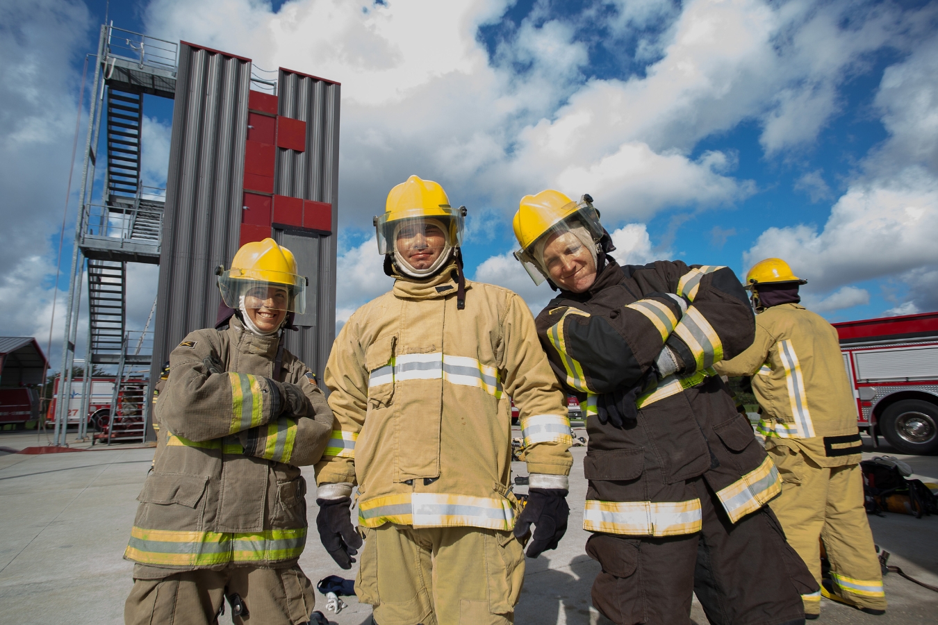Group photo of fire fighter student recruits posing in front of the fire academy tower during a group activity