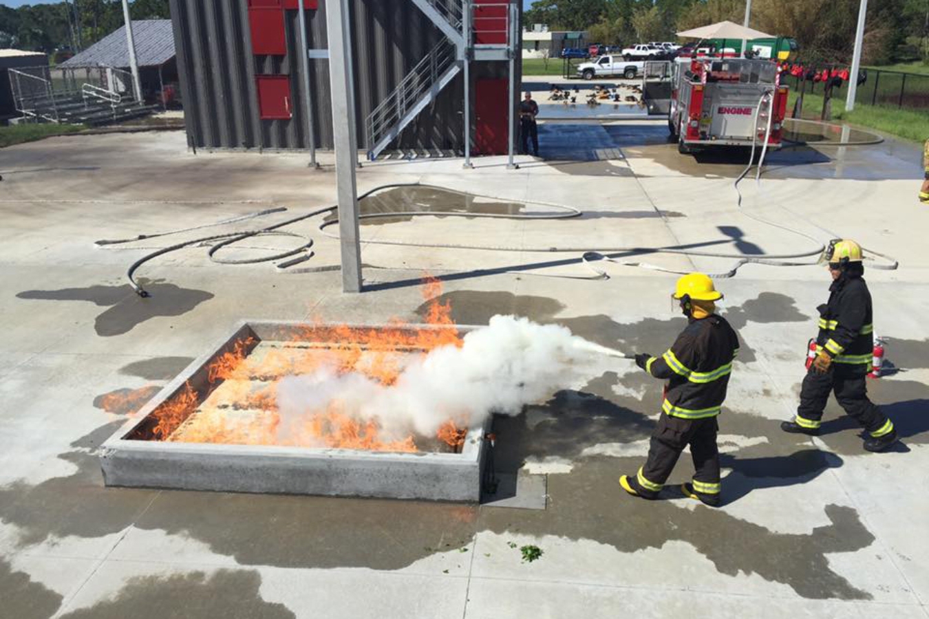 Firefighter students work together to put out a controlled fire