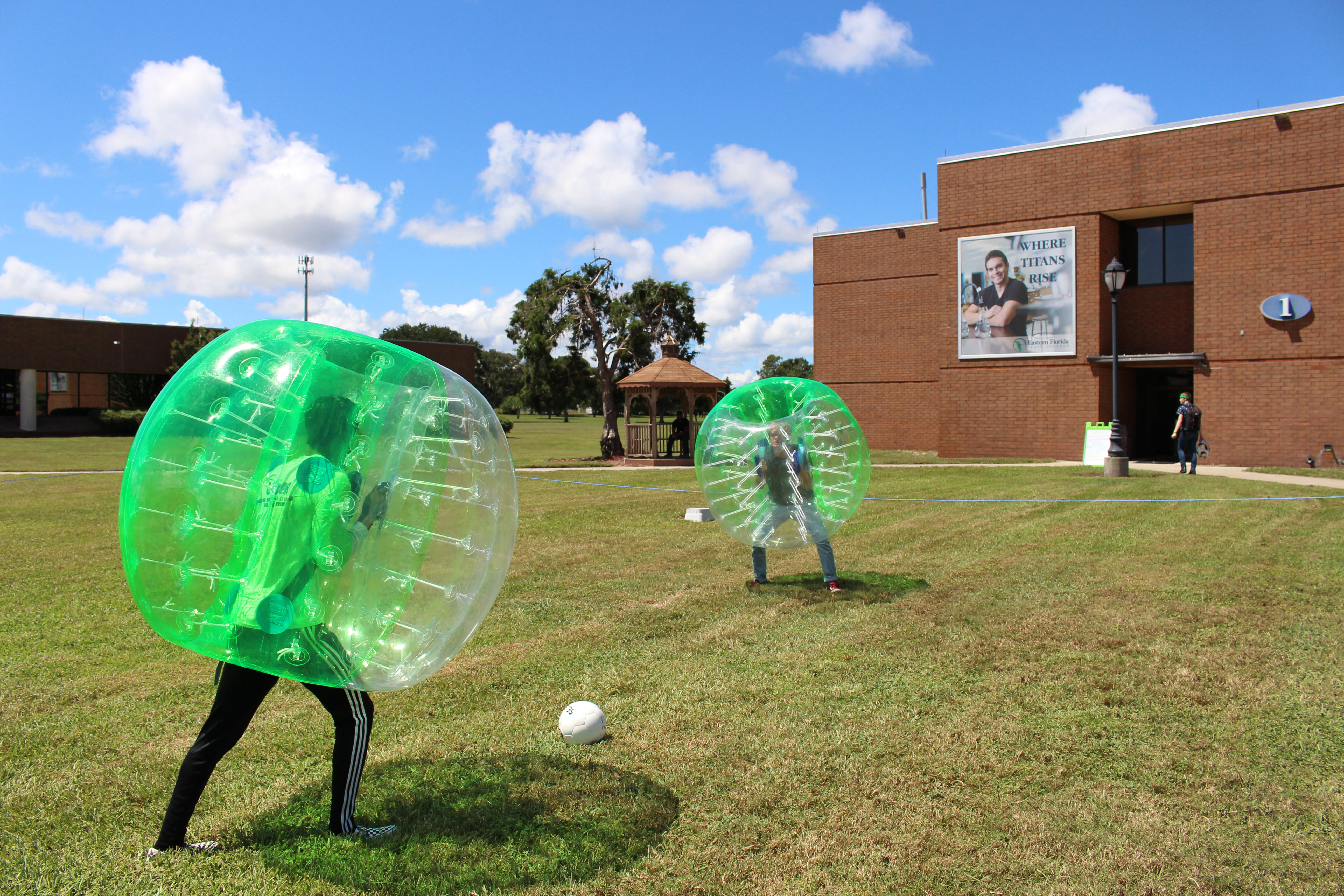 Two students playing soccer on the Titusville Campus while wearing bumper balls