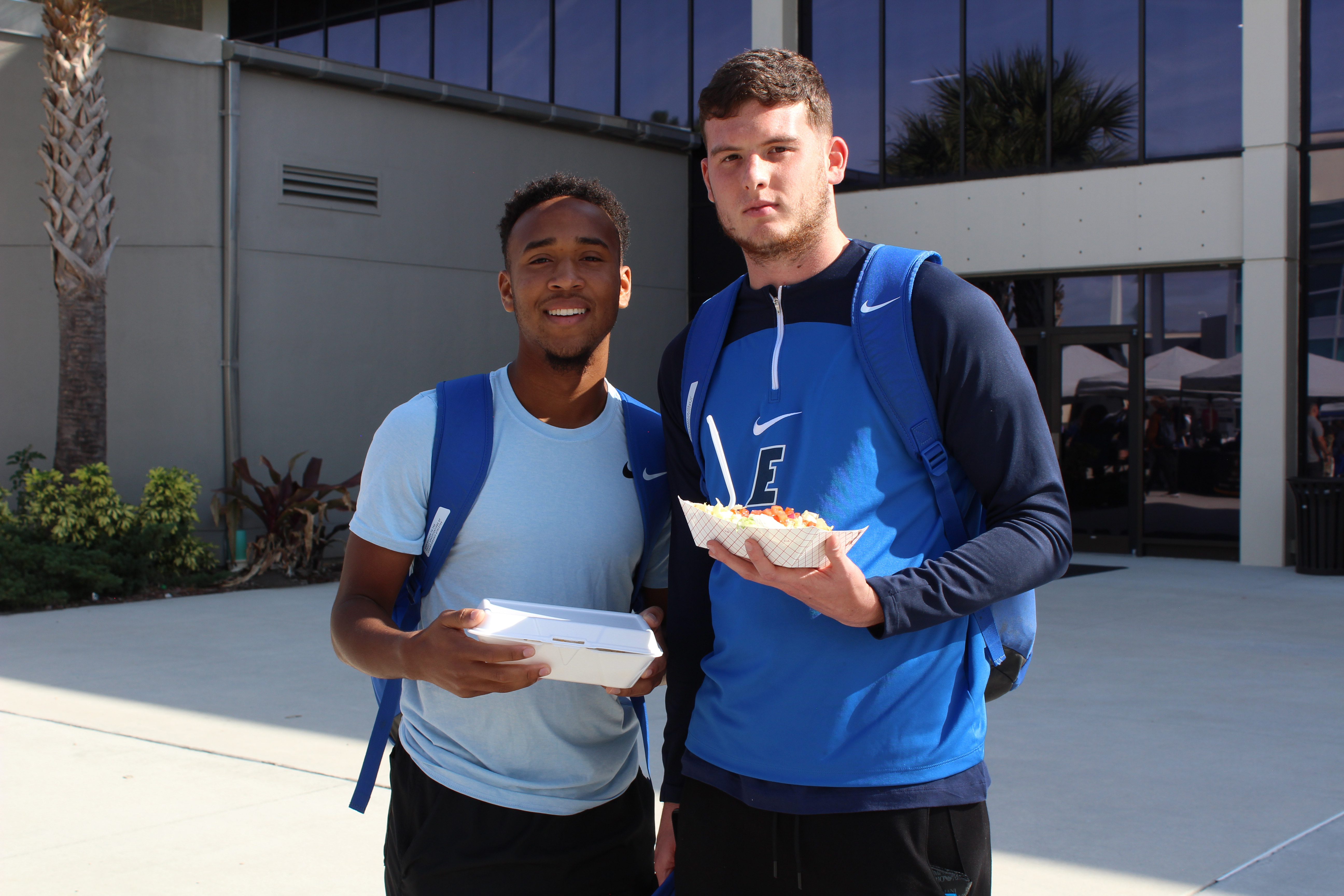 Two male students on the Melbourne campus enjoying free food from a student event