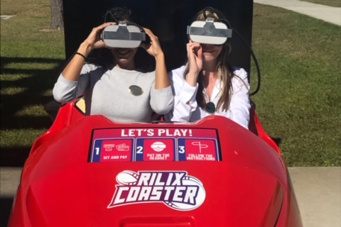 Two female students sitting in a virtual rollercoaster activity at a student event