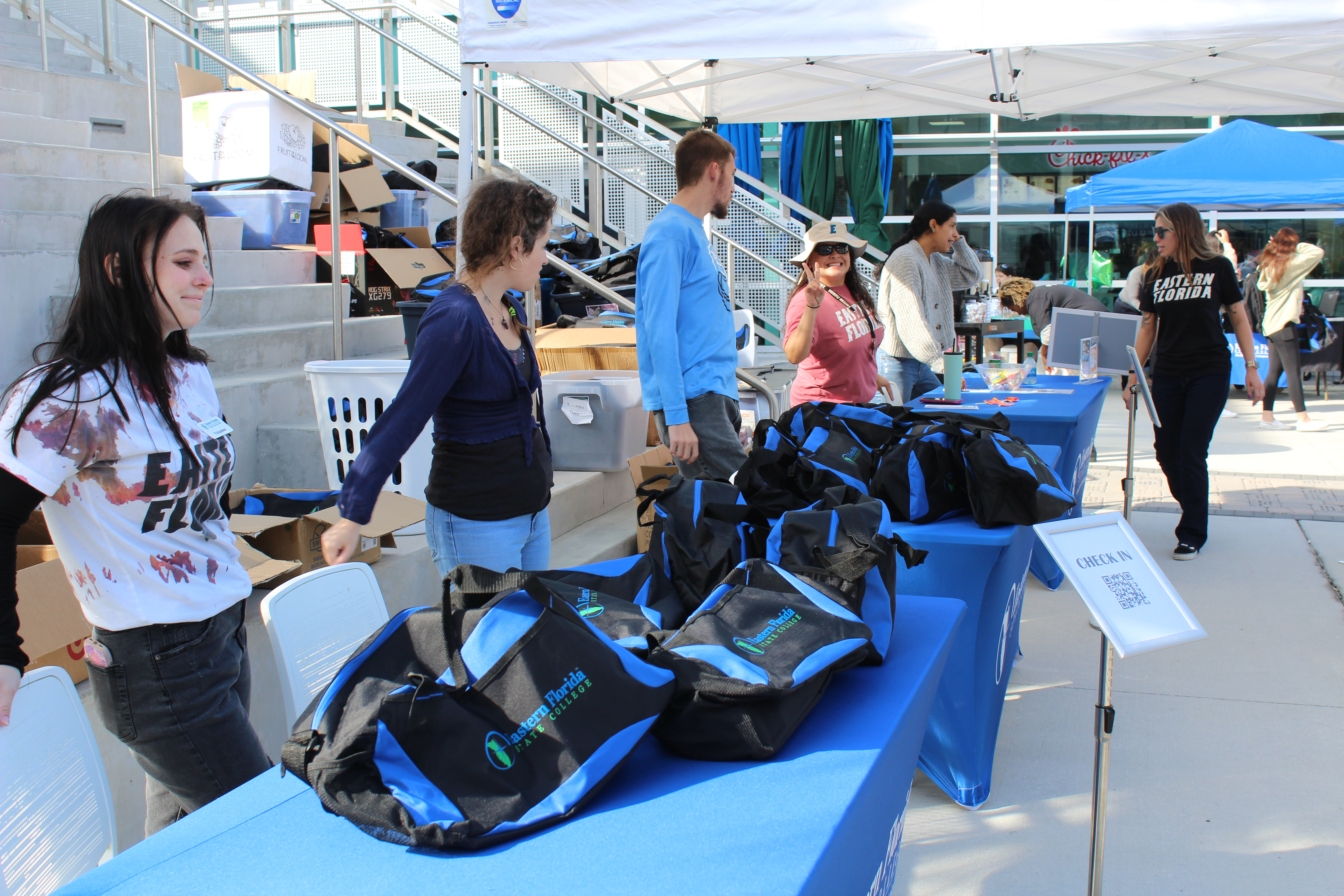 Student Government members line up at a check-in table with free EFSC goodies to kick-off an outdoor student event on the Melbourne Campus.