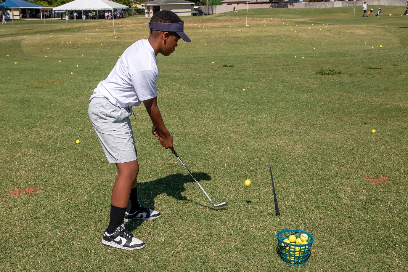 A young boy is practicing his stance while holding a golf club