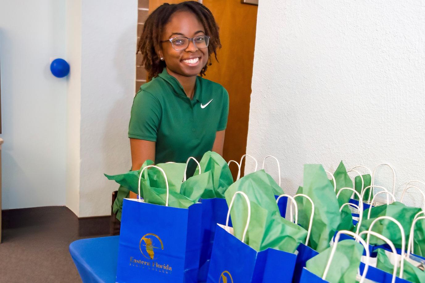 A girl is smiling next to a table with EFSC goodie bags on it