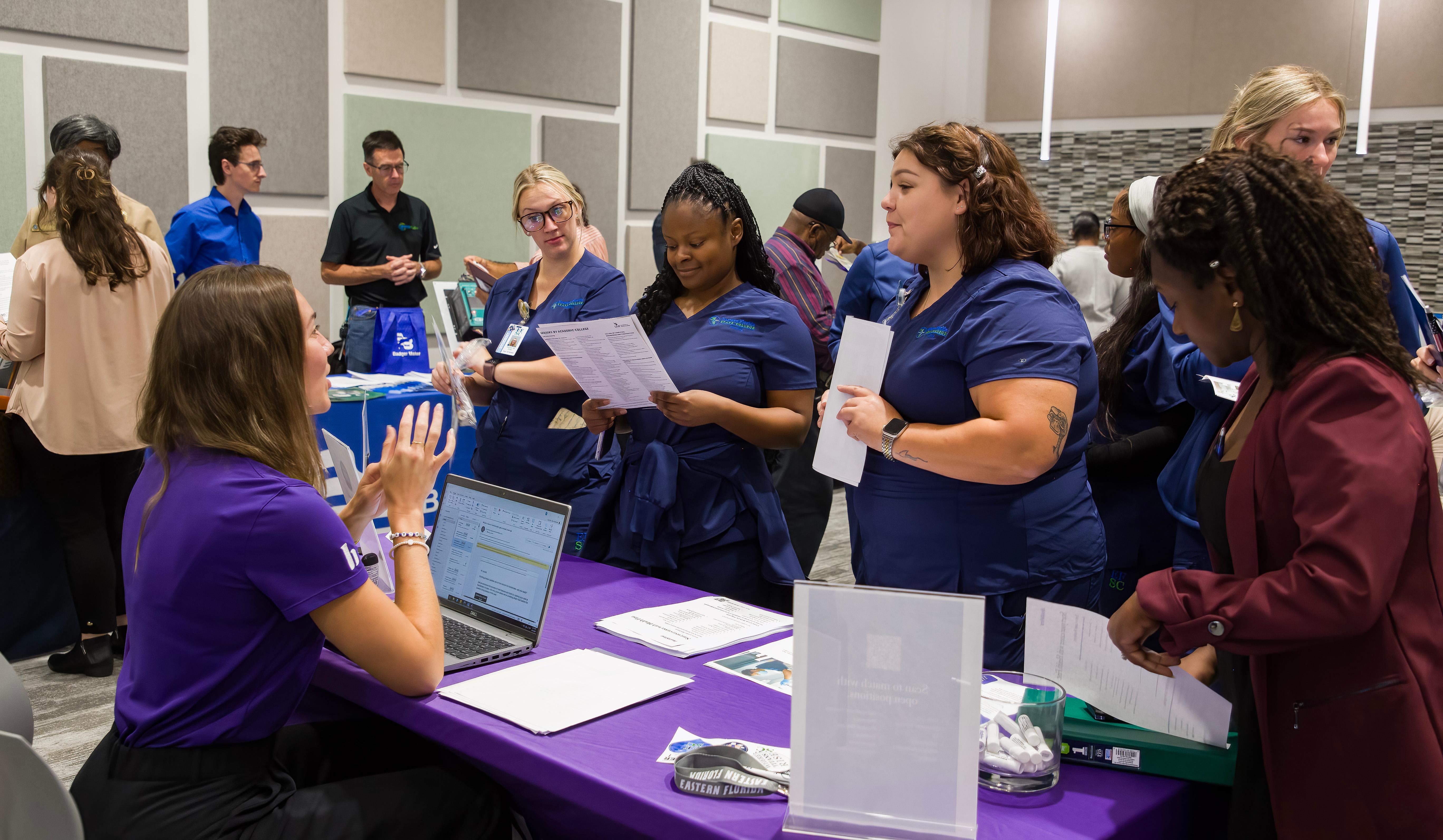A student talks with employers at a table at the job fair