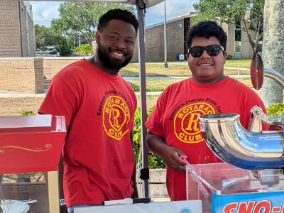 Two students wearing Rotaract shirts are smiling at the camera