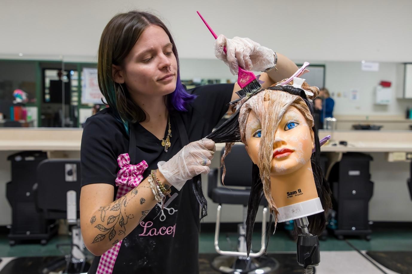 cosmetology student working with a mannequin head