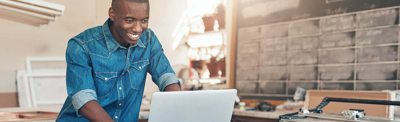 African American man looking at computer, smiling.