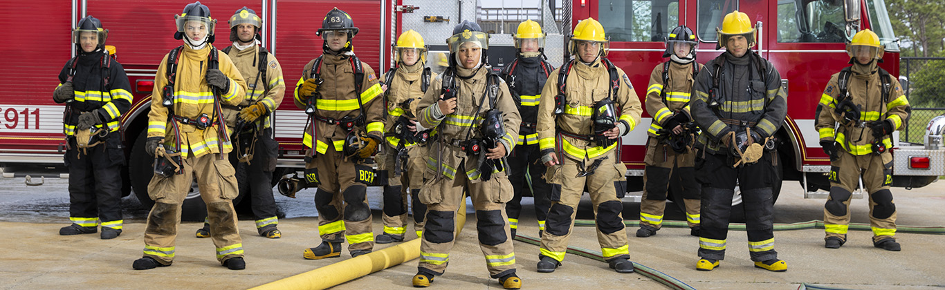Fire fighter students posing in a line in front of a fire truck