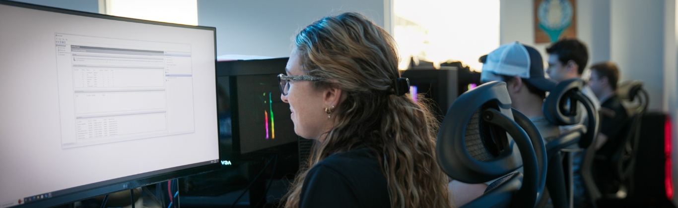 Students sit in front of glowing computer screens doing a class