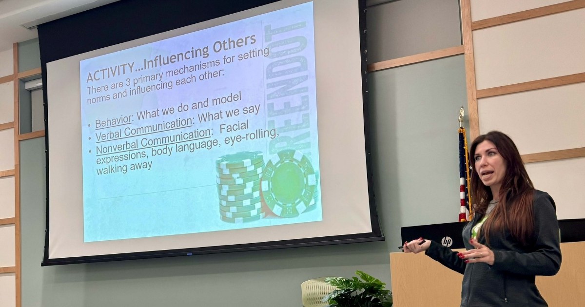 Woman speaking with a powerpoint in the background