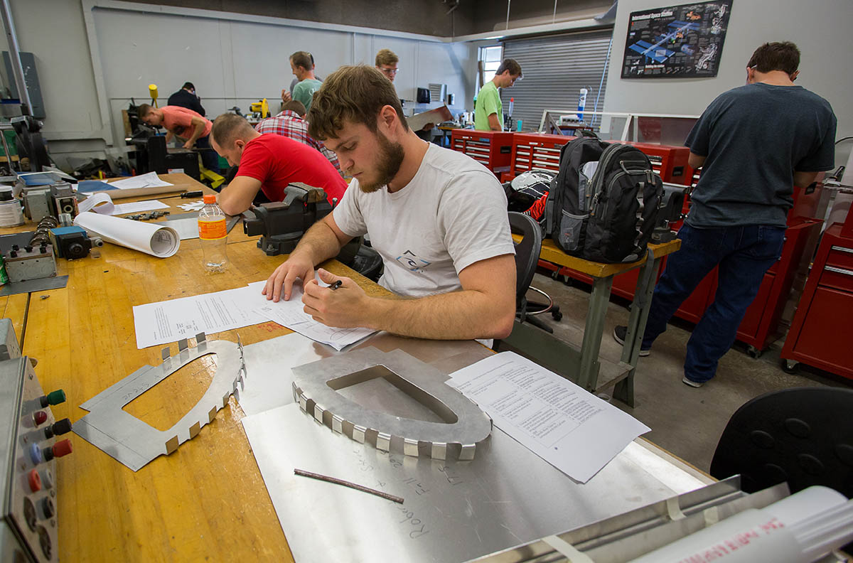 Students with graphing rulers and machine equipment in background