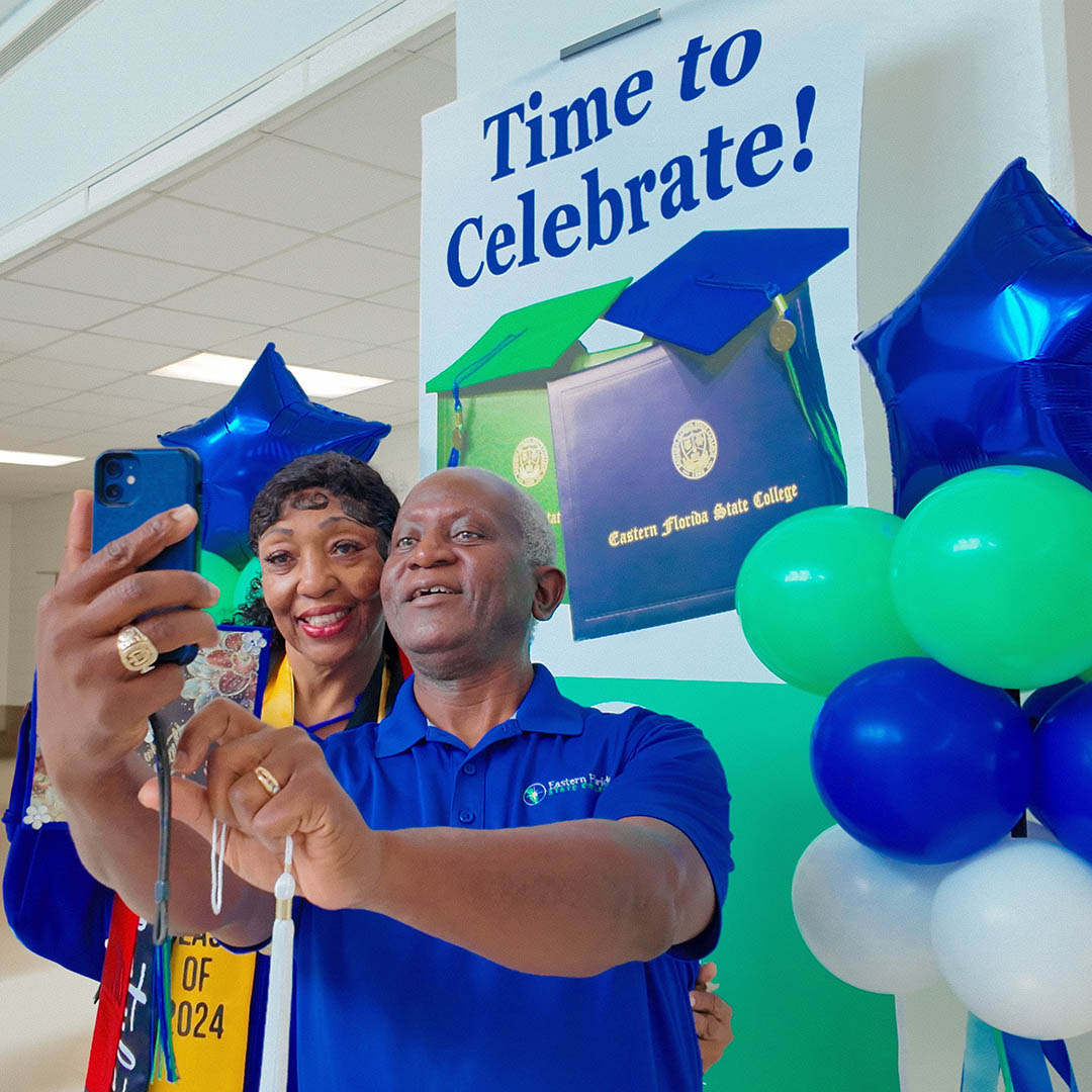 female graduate with man taking selfie image with phone