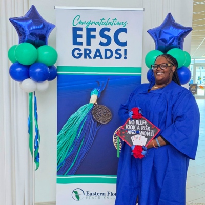 Alexis Hankerson holds a decorated graduation cap that says "No bluff. Took a risk and won!" featuring a deck of cards.