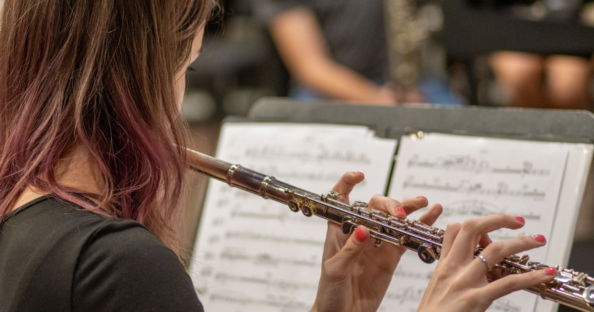 A female student playing a flute to sheet music