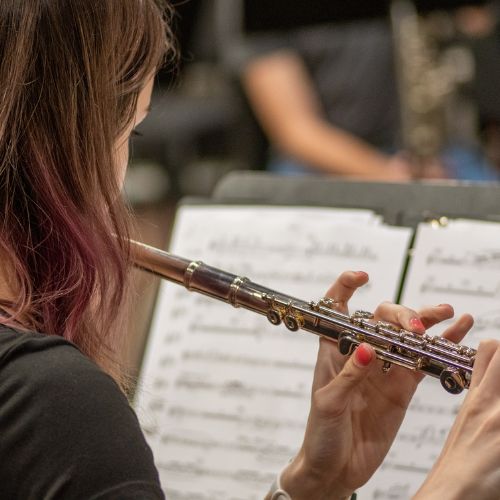 A female student playing a flute to sheet music