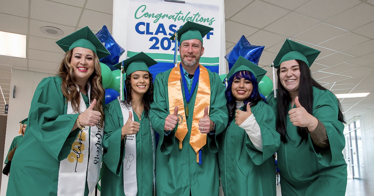 five graduates in caps and gowns