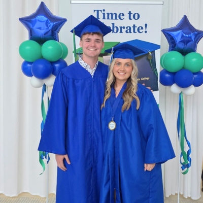 Evan and Karleigh Burnette - Evan is taller than Karleigh. Evan has short brown hair and Karleigh has long wavy blonde hair. Both are wearing blue graduation gowns.