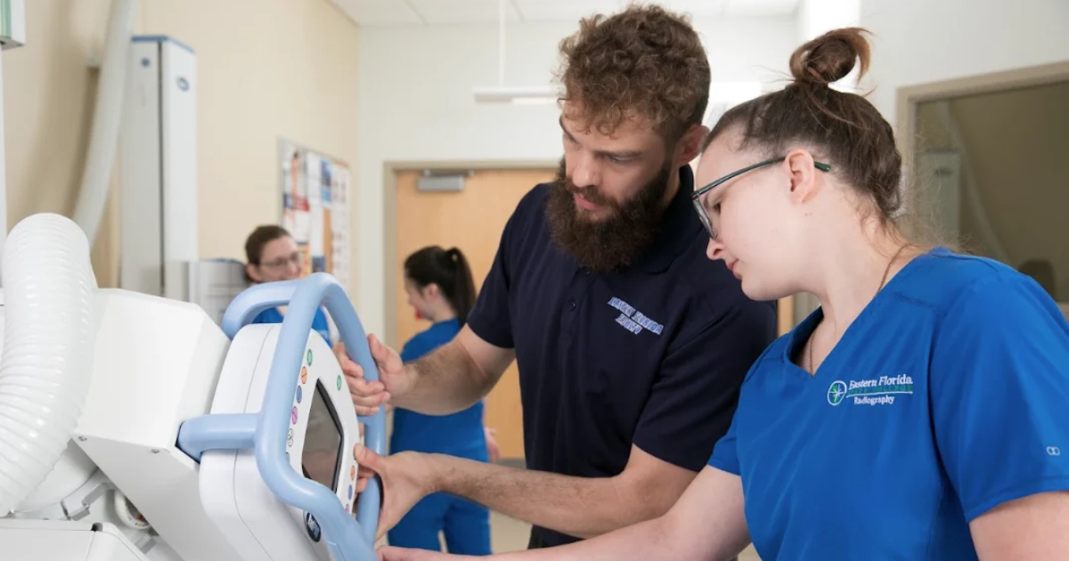 An image of two radiography students working with a machine in a lab