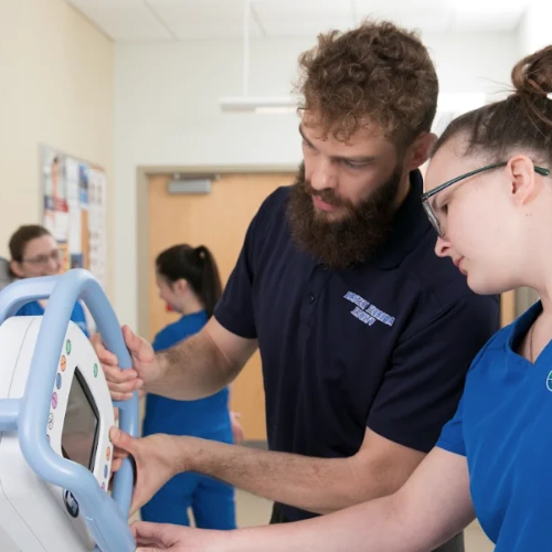 An image of two radiography students working with a machine in a lab