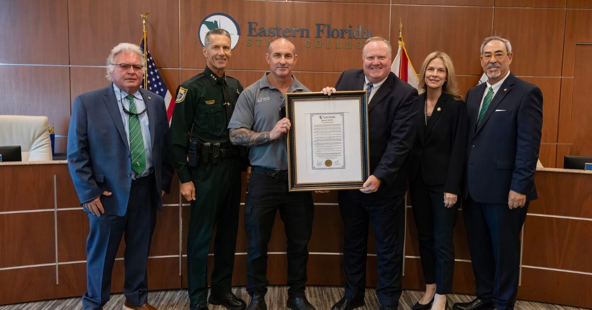EFSC President stands with members of City of Cocoa Beach Fire Department holding commemorative framed donation.