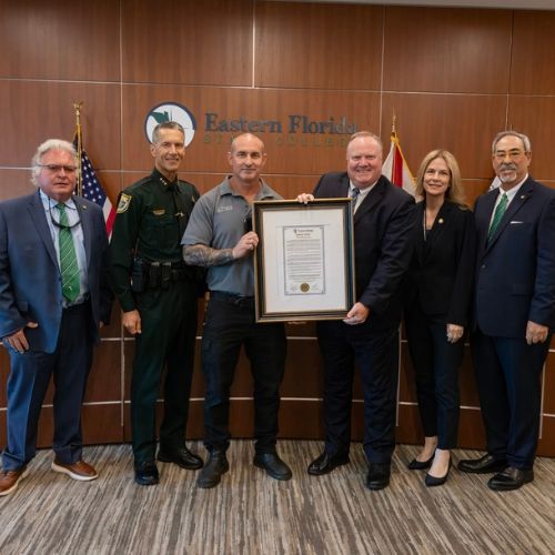 EFSC President stands with members of City of Cocoa Beach Fire Department holding commemorative framed donation.