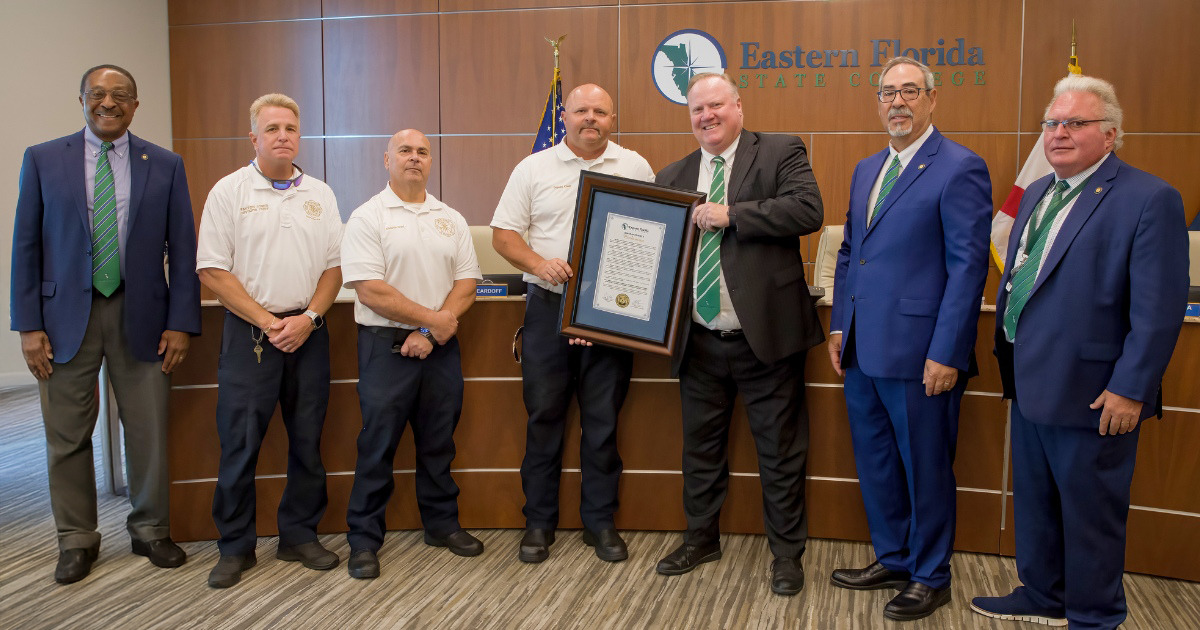 Seven men holding a framed certificate