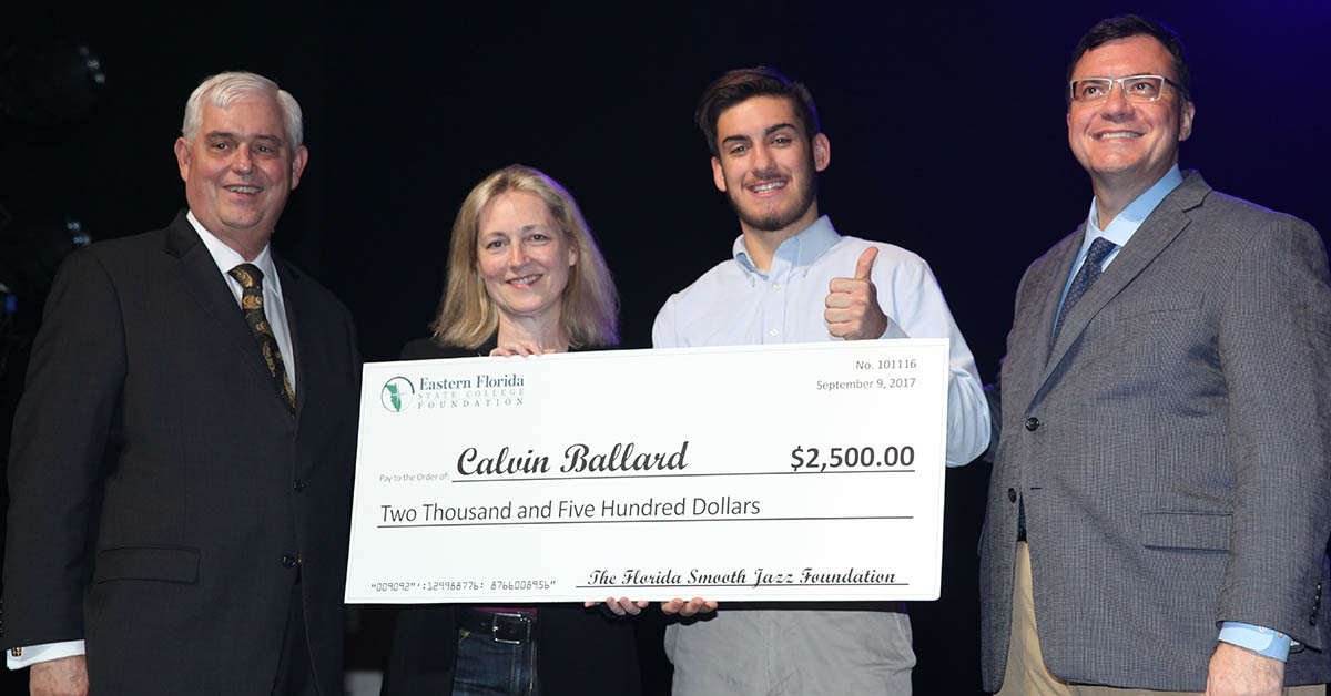 Three adults presenting scholarship check to student