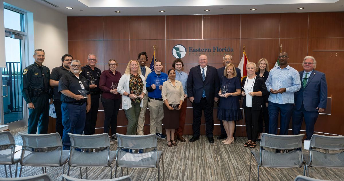An image of twelve EFSC employees standing with President Jim Richey, holding their STARS awards.